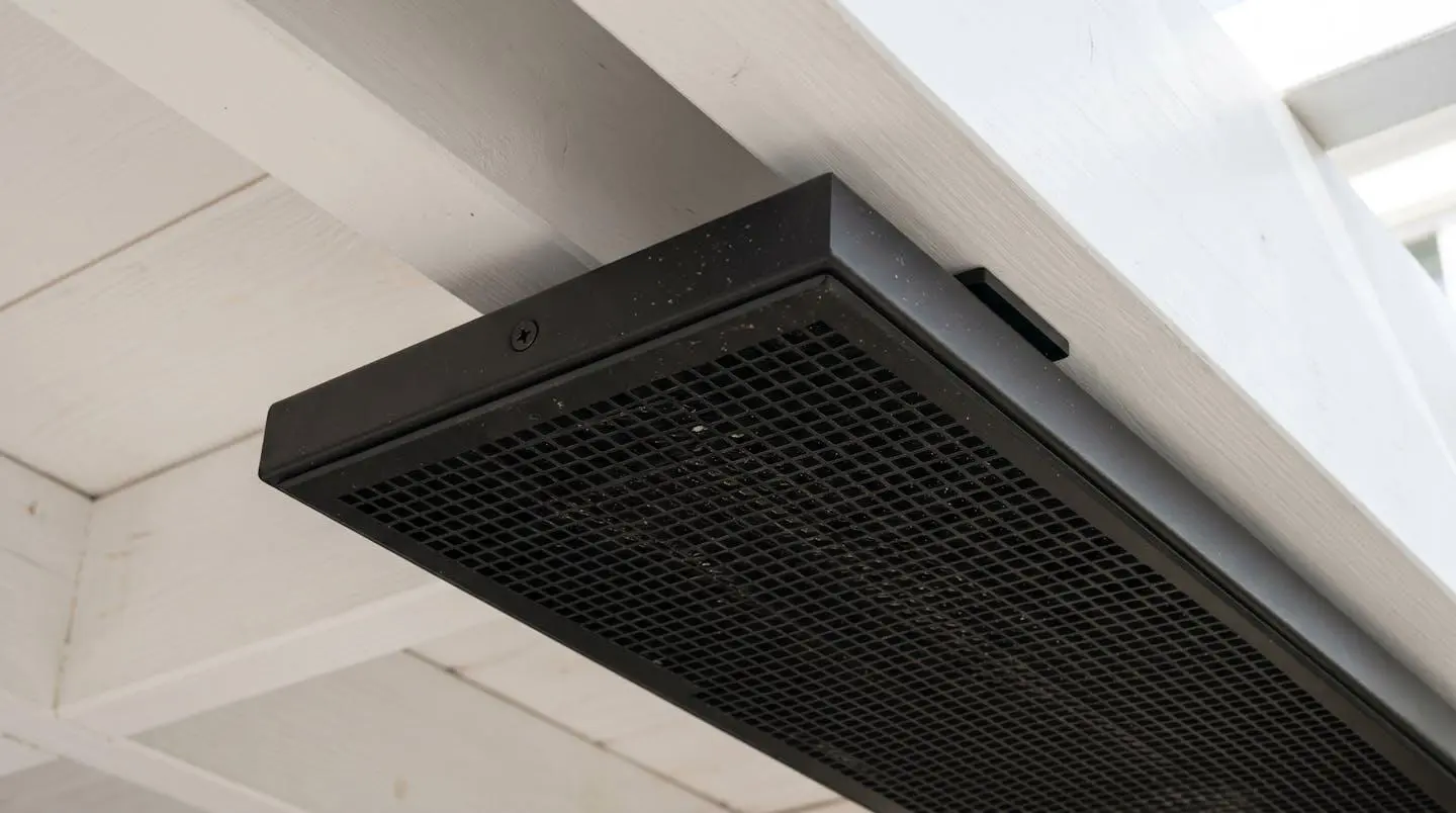 Radiateur infrarouge extra-plat noir mat installé sous plafond de pergola blanche, design discret et finition aluminium