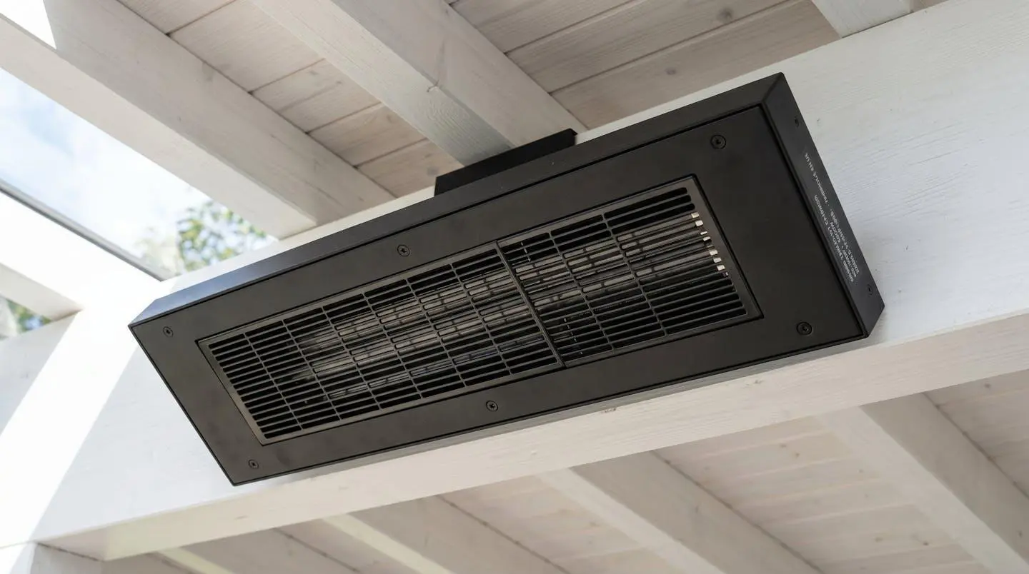 Radiateur infrarouge extra-plat noir mat installé sous plafond de pergola blanche, design discret et finition aluminium
