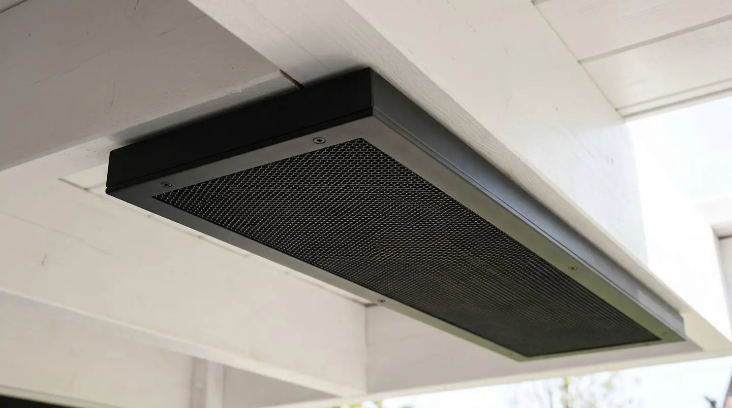 Radiateur infrarouge extra-plat noir mat installé sous plafond de pergola blanche, design discret et finition aluminium