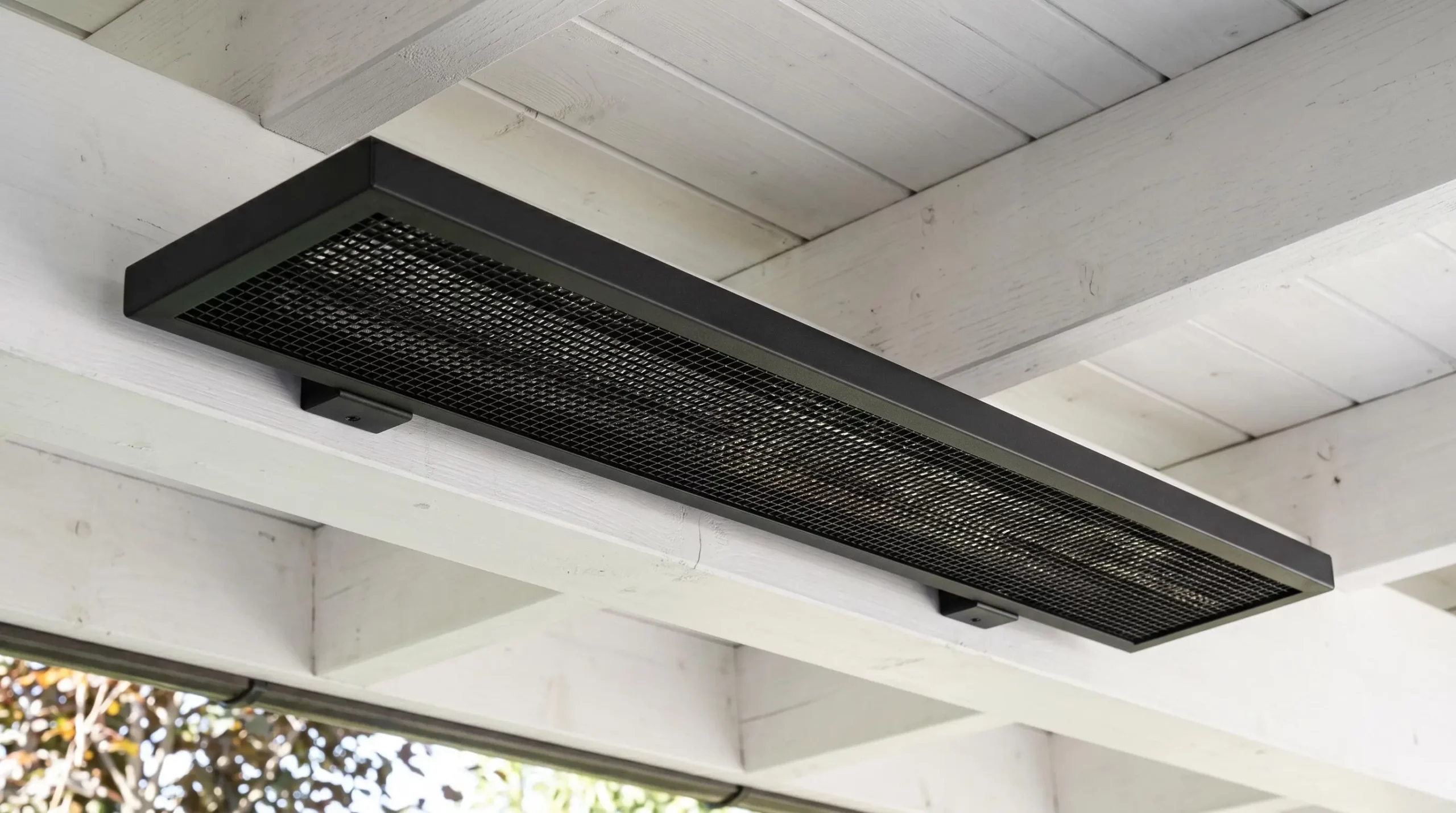 Radiateur infrarouge extra-plat noir mat installé sous plafond de pergola blanche, design discret et finition aluminium