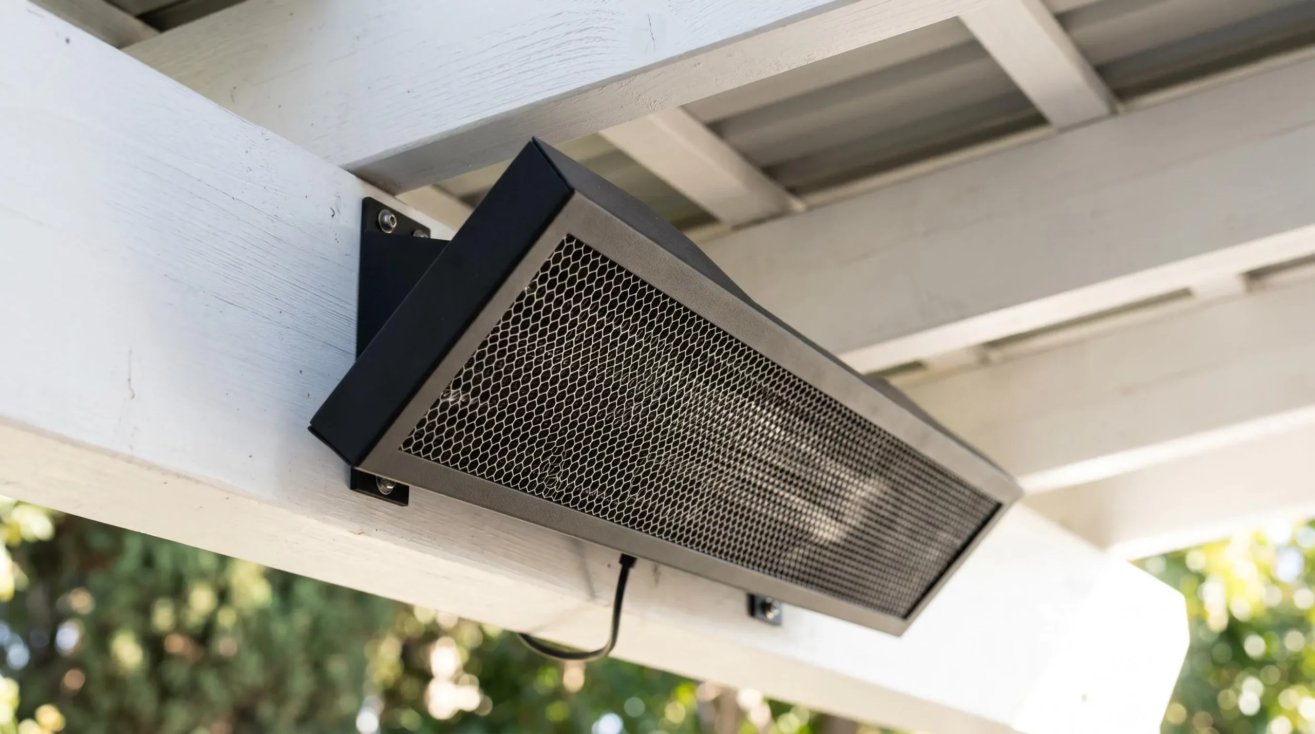 Radiateur infrarouge extra-plat noir mat installé sous plafond de pergola blanche, design discret et finition aluminium