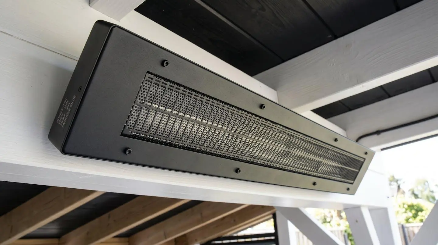 Radiateur infrarouge extra-plat noir mat installé sous plafond de pergola blanche, design discret et finition aluminium